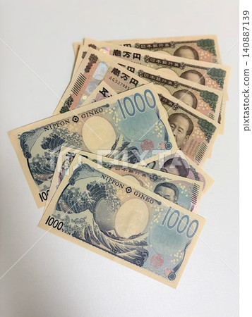 A 10,000 yen bill and a 1,000 yen bill spread out in a fan shape. A 10,000 yen bill and a 1,000 yen bill spread out in a fan shape. 140887139