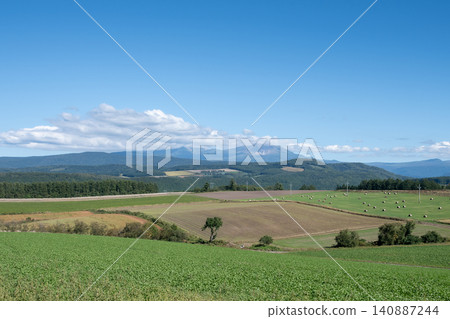 Farmland and mountain peaks on a sunny summer day, Mt. Daisetsu Farmland and mountain peaks on a sunny summer day, Mt. Daisetsu 140887244