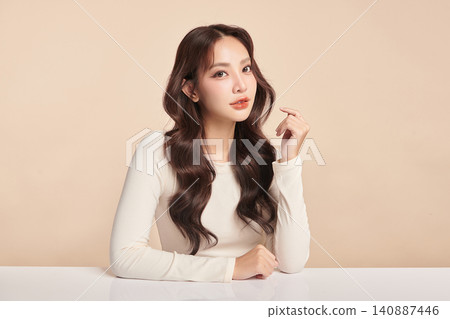 A beautiful young Asian woman with clean, fresh skin against a beige background. Skincare, facial treatment, cosmetology, beauty, and spa. An elegant portrait of an Asian woman. 140887446