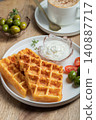 Crunchy waffle fries with sour cream dip served in a basket 140887717