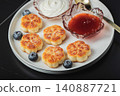 Cottage cheese pancakes, syrniki, curd fritters decorated with strawberry and raspberry served on a white plate. Homemade breakfast concept 140887721