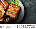 Hot grilled spare ribs from a summer BBQ served on a plate with sauce. Top view. Copy space 140887722