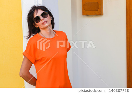 Woman in vibrant orange dress standing on the doorstep of her welcoming home in soft natural daylight Woman in vibrant orange dress standing on the doorstep of her welcoming home in soft natural daylight 140887728