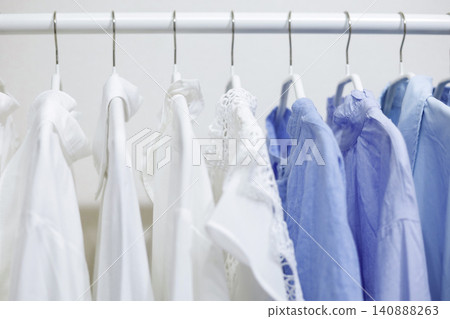 A hanger rack filled with tops in refreshing white and blue colors. A hanger rack filled with tops in refreshing white and blue colors. 140888263