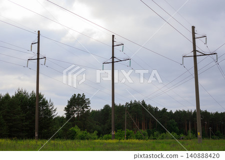 High-voltage power lines against a backdrop of pine forest. Long power line pylons stretch High-voltage power lines against a backdrop of pine forest. Long power line pylons stretch 140888420