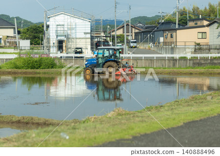 Farmers performing pre-planting work in a residential area: plowing the rice paddies. Farmers performing pre-planting work in a residential area: plowing the rice paddies. 140888496