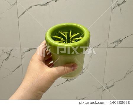 Close-up green paw washer cup for dog, Welsh Corgi cleaning paws after walk, pet hygiene and care concept at home Close-up green paw washer cup for dog, Welsh Corgi cleaning paws after walk, pet hygiene and care concept at home 140888658