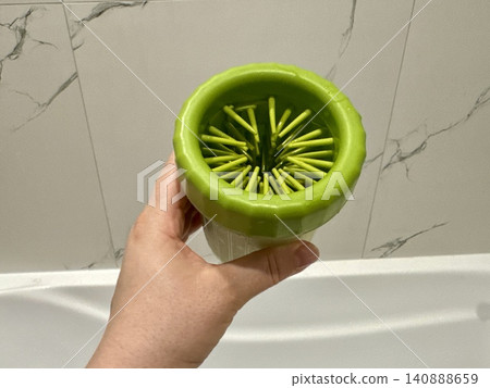 Close-up green paw washer cup for dog, Welsh Corgi cleaning paws after walk, pet hygiene and care concept at home Close-up green paw washer cup for dog, Welsh Corgi cleaning paws after walk, pet hygiene and care concept at home 140888659