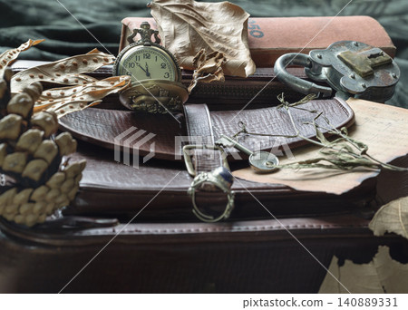 A storied collection rests in the dim light of memory. A pocket watch, a skeleton key, and a rusted lock crown a leather satchel, nestled among charred scraps of music and withered flora. It is a A storied collection rests in the dim light of memory. A pocket watch, a skeleton key, and a rusted lock crown a leather satchel, nestled among charred scraps of music and withered flora. It is a 140889331