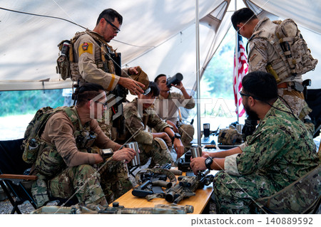 Close up shot group of army with different types of equipment and weapons have meeting and plan inside field tent. Close up shot group of army with different types of equipment and weapons have meeting and plan inside field tent. 140889592