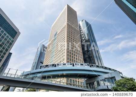 Low-angle view of a New Transit Yurikamome line train running on the elevated track with modern skyscrapers in Shiodome, Minato, Tokyo, Japan. It's an automated guideway transit service in Tokyo. Low-angle view of a New Transit Yurikamome line train running on the elevated track with modern skyscrapers in Shiodome, Minato, Tokyo, Japan. It's an automated guideway transit service in Tokyo. 140889670