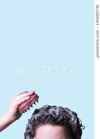 Pink scalp massager brush for hair treatment and care in human hand on blue background Pink scalp massager brush for hair treatment and care in human hand on blue background 140889746