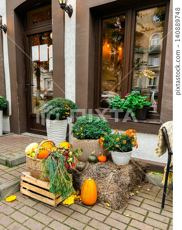 Halloween decoration of cafe entrance celebrating October holidays. Pumpkins and flowers on restaurant terrace Halloween decoration of cafe entrance celebrating October holidays. Pumpkins and flowers on restaurant terrace 140889748