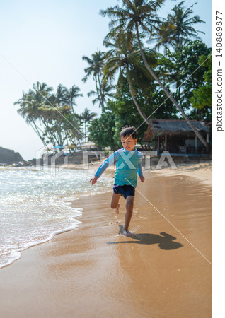Joyful 5-Year-Old Boy Running on Sandy Beach in Sri Lanka Under Bright Sunlight Joyful 5-Year-Old Boy Running on Sandy Beach in Sri Lanka Under Bright Sunlight 140889877