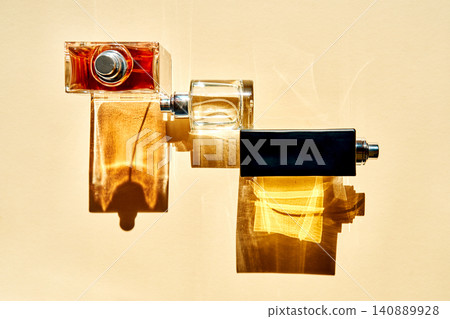 Three luxury perfume bottles casting long shadows on a beige wall Three luxury perfume bottles casting long shadows on a beige wall 140889928