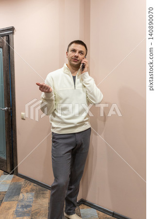 Man talking on smartphone at home. Thirty eight year old businessman discussing project during remote work. Professional lifestyle, communication and freelance technology concept. Man talking on smartphone at home. Thirty eight year old businessman discussing project during remote work. Professional lifestyle, communication and freelance technology concept. 140890070