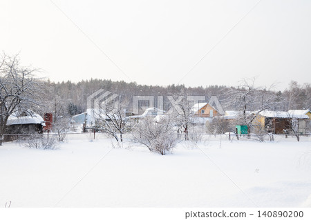 Christmas landscape in the village. Winter landscape featuring snow covered houses and trees in a quiet rural area during a snowfall. Christmas landscape in the village. Winter landscape featuring snow covered houses and trees in a quiet rural area during a snowfall. 140890200