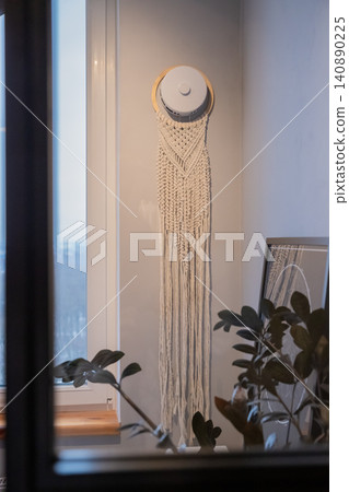 macrame wall hanging on supply air valve on wall, window and potted plant macrame wall hanging on supply air valve on wall, window and potted plant 140890225
