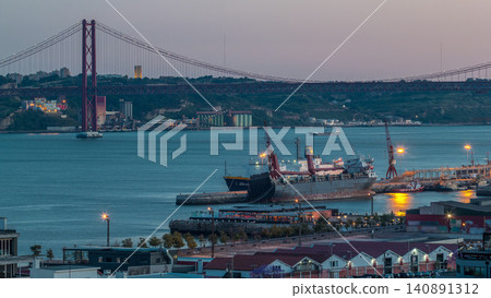 Skyline over Lisbon commercial port day to night timelapse, 25th April Bridge, containers on pier with freight cranes Skyline over Lisbon commercial port day to night timelapse, 25th April Bridge, containers on pier with freight cranes 140891312