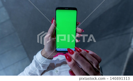 Female teen girl with red nails using smartphone with green screen staying outdoors. 140891313