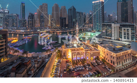 Yachts in Dubai Marina flanked by the Al Rahim Mosque and residential towers and skyscrapers aerial day to night timelapse. Yachts in Dubai Marina flanked by the Al Rahim Mosque and residential towers and skyscrapers aerial day to night timelapse. 140891415