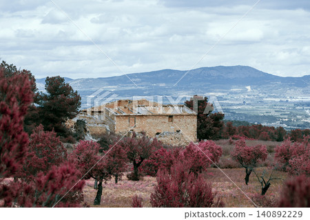 Rustic stone building in scenic mountain landscape with pink blossoming trees Rustic stone building in scenic mountain landscape with pink blossoming trees 140892229
