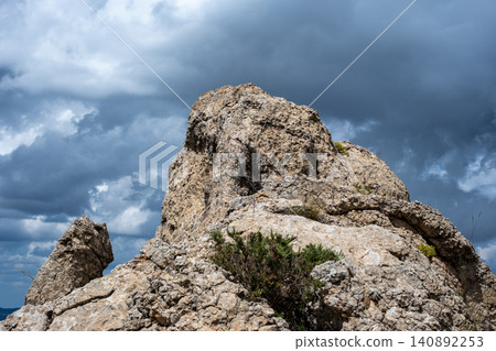 Majestic rocky cliff under dramatic cloudy sky capturing nature's raw beauty Majestic rocky cliff under dramatic cloudy sky capturing nature's raw beauty 140892253