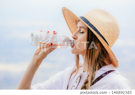 Woman in sun hat enjoying refreshing drink outdoors on a sunny day Woman in sun hat enjoying refreshing drink outdoors on a sunny day 140892385