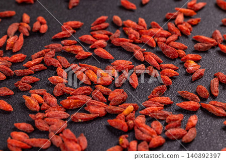 Dried goji berries scattered on a dark surface Dried goji berries scattered on a dark surface 140892397