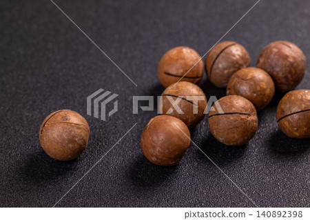 Macadamia nuts resting on a dark surface Macadamia nuts resting on a dark surface 140892398
