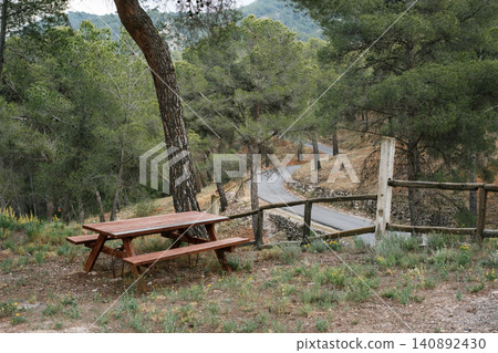 Serene picnic area overlooking winding forest road in mountain landscape Serene picnic area overlooking winding forest road in mountain landscape 140892430