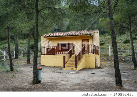 Charming rustic cabin in forest setting with porch and stairs surrounded by trees Charming rustic cabin in forest setting with porch and stairs surrounded by trees 140892433