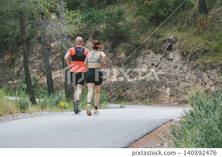 Fit couple running on forest road for outdoor exercise and fitness motivation Fit couple running on forest road for outdoor exercise and fitness motivation 140892476
