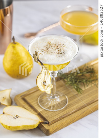Pear Elderflower Cocktail. Champagne coupe glass filled with pear puree cocktail or mocktails surrounded by ingredients and bar tools 140892527