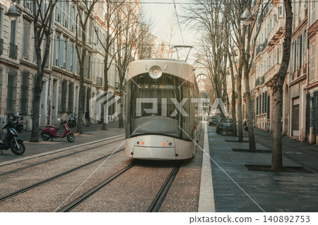 Modern tram on tree-lined street during winter in european city 140892753
