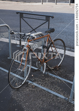 Rusty old bicycle locked in urban setting displays vandalism and weathered decay Rusty old bicycle locked in urban setting displays vandalism and weathered decay 140892754