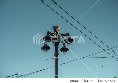 Vintage street lamp with clear blue sky and overhead electrical cables Vintage street lamp with clear blue sky and overhead electrical cables 140892783