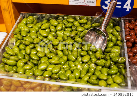 Assorted green candied almonds in bulk display with metal scoop in a candy store Assorted green candied almonds in bulk display with metal scoop in a candy store 140892815