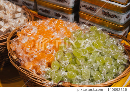 Colorful wrapped hard candies in wicker baskets at a market display Colorful wrapped hard candies in wicker baskets at a market display 140892816