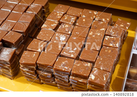 Delicious caramel fudge squares displayed in confectionery store with smooth and nutty variants 140892818