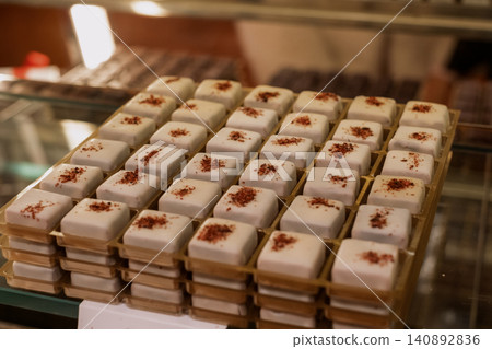 Assorted gourmet white chocolate confections with red sprinkles in bakery display Assorted gourmet white chocolate confections with red sprinkles in bakery display 140892836