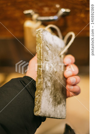 Hand holding rustic cutting board in cozy kitchen environment Hand holding rustic cutting board in cozy kitchen environment 140892869