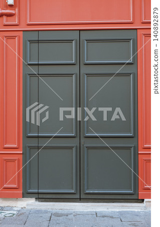 Elegant urban architecture featuring bold red wall and classic dark green door Elegant urban architecture featuring bold red wall and classic dark green door 140892879