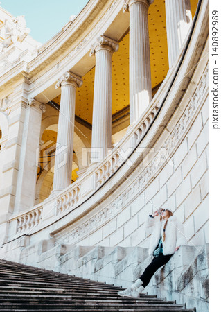 Woman relaxing on architectural steps with classical columns in elegant urban setting Woman relaxing on architectural steps with classical columns in elegant urban setting 140892989