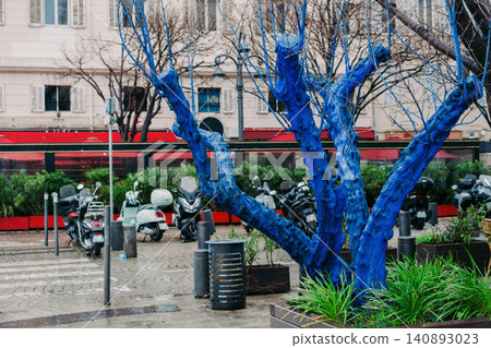 Striking urban scene with blue painted tree and motorbikes in cityscape Striking urban scene with blue painted tree and motorbikes in cityscape 140893023