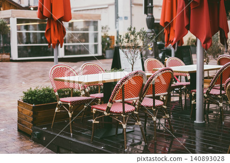 Outdoor cafe with red chairs and wooden tables in cozy urban setting Outdoor cafe with red chairs and wooden tables in cozy urban setting 140893028
