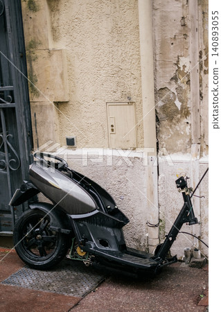 Abandoned e-scooter leaning against weathered urban wall Abandoned e-scooter leaning against weathered urban wall 140893055