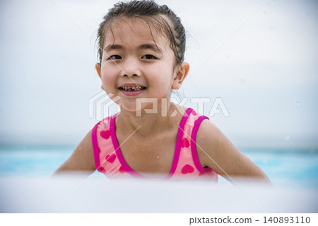 Portrait Girl in pink swimsuit playful in swimming pool summer time with pink swimwear, blue water at hotel swimming pool outdoor. Toddler girl Kid smile laugh look at camera. Happy girl swim playful Portrait Girl in pink swimsuit playful in swimming pool summer time with pink swimwear, blue water at hotel swimming pool outdoor. Toddler girl Kid smile laugh look at camera. Happy girl swim playful 140893110