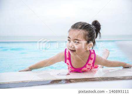 Portrait Girl in pink swimsuit playful in swimming pool summer time with pink swimwear, blue water at hotel swimming pool outdoor. Toddler girl Kid smile laugh look at camera. Happy girl swim playful Portrait Girl in pink swimsuit playful in swimming pool summer time with pink swimwear, blue water at hotel swimming pool outdoor. Toddler girl Kid smile laugh look at camera. Happy girl swim playful 140893111