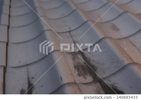 Black grime has accumulated in the grooves of the roof tiles. The roof tiles are deteriorating and dirty. Maintenance is needed. Black grime has accumulated in the grooves of the roof tiles. The roof tiles are deteriorating and dirty. Maintenance is needed. 140893433